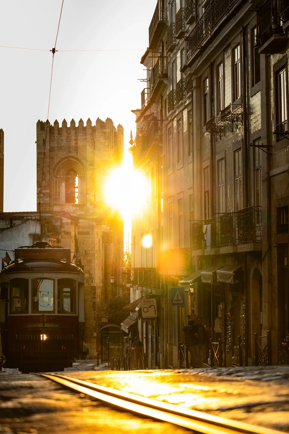 Sunlight between old buildings and a tram in Lisbon